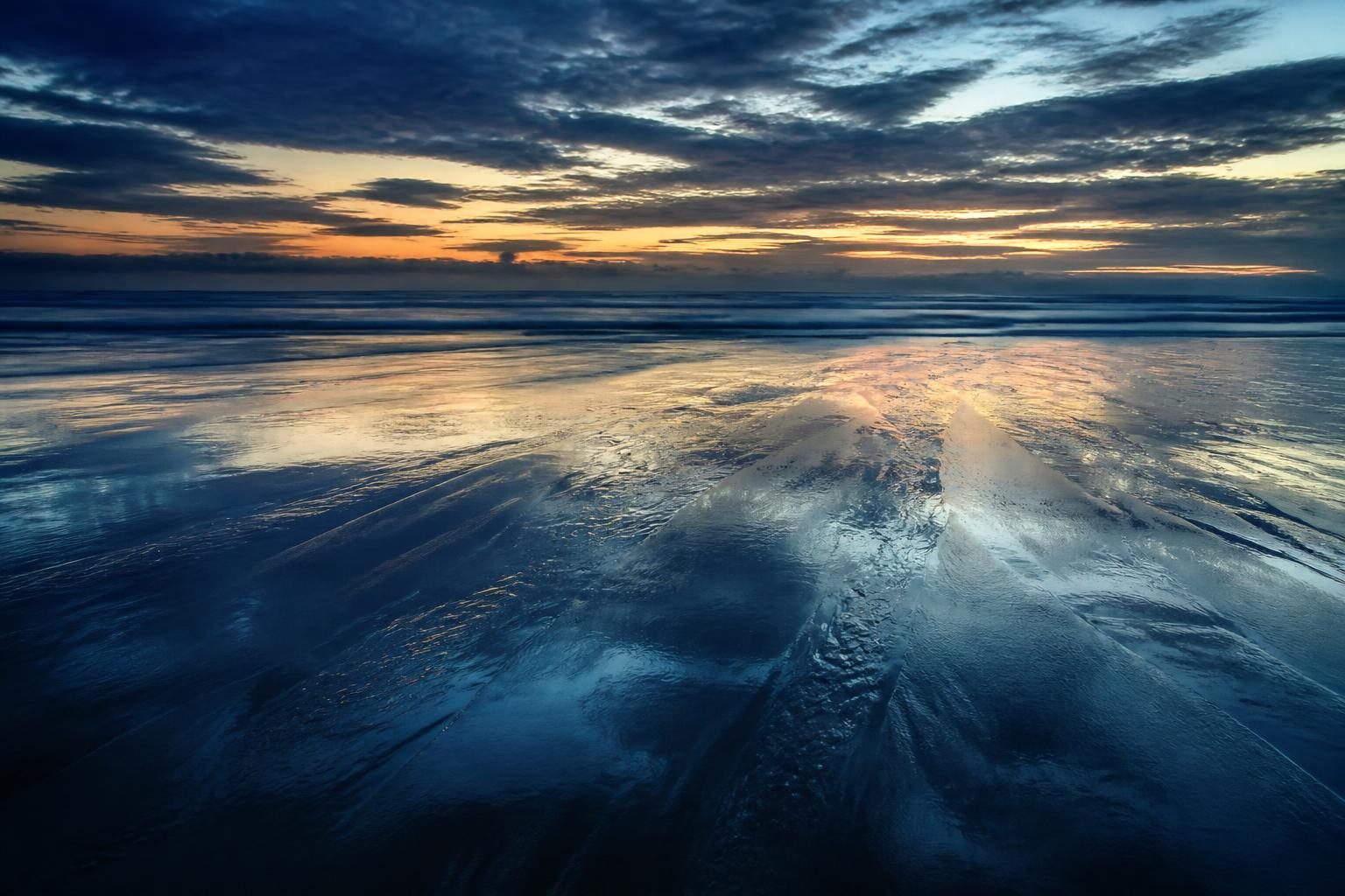 Wet sand reflecting a dusk sky